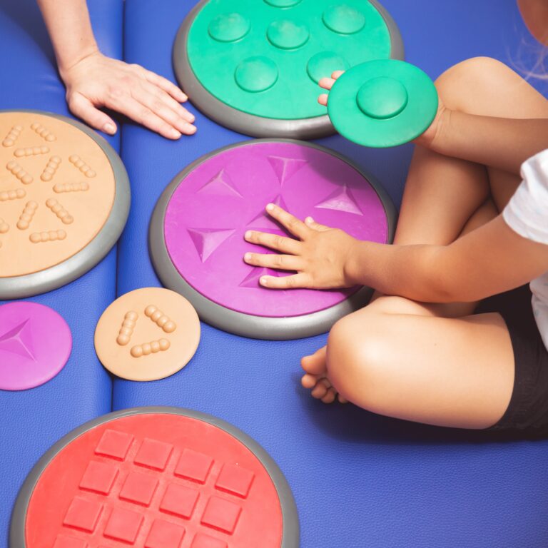 Child with occupational therapist touching sensory integration equipment